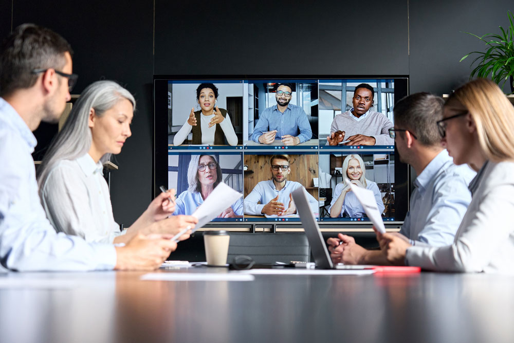 People attending a virtual meeting in front of a screen
